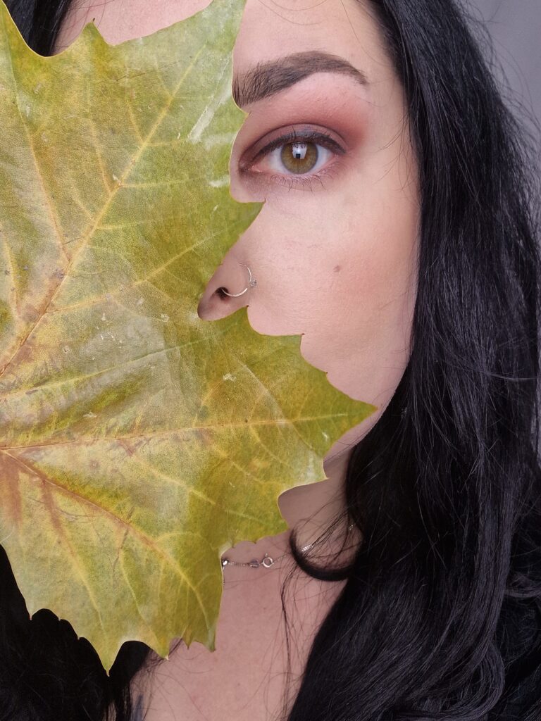 how to take good photos with your phone - selfie of woman holding autumn leaf in front of face