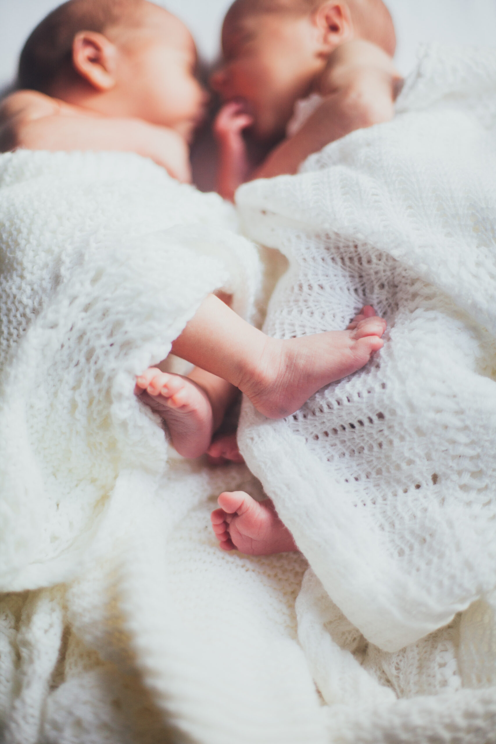 Picture of twin newborns with focus on their tiny feet. 