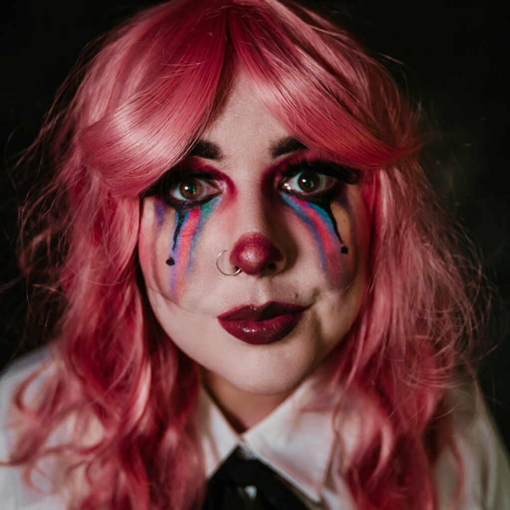 Self portrait of woman with clown makeup and pink wig