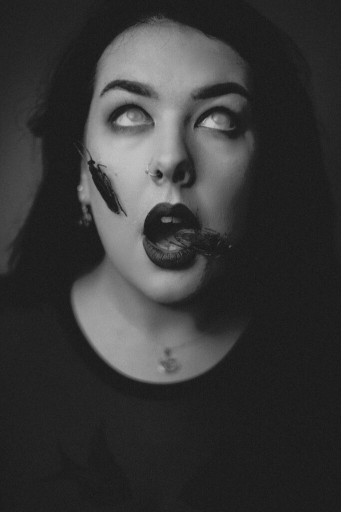 Woman posing with fake cockroaches on face to depict a self portrait of a nightmare or phobia