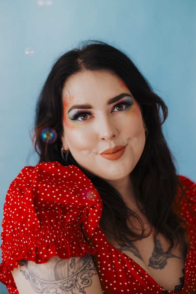 A creative self-portrait of a woman against a blue background, surrounded by soft natural light and bubbles, showcasing the essence of a Self Portrait Photo Challenge.
