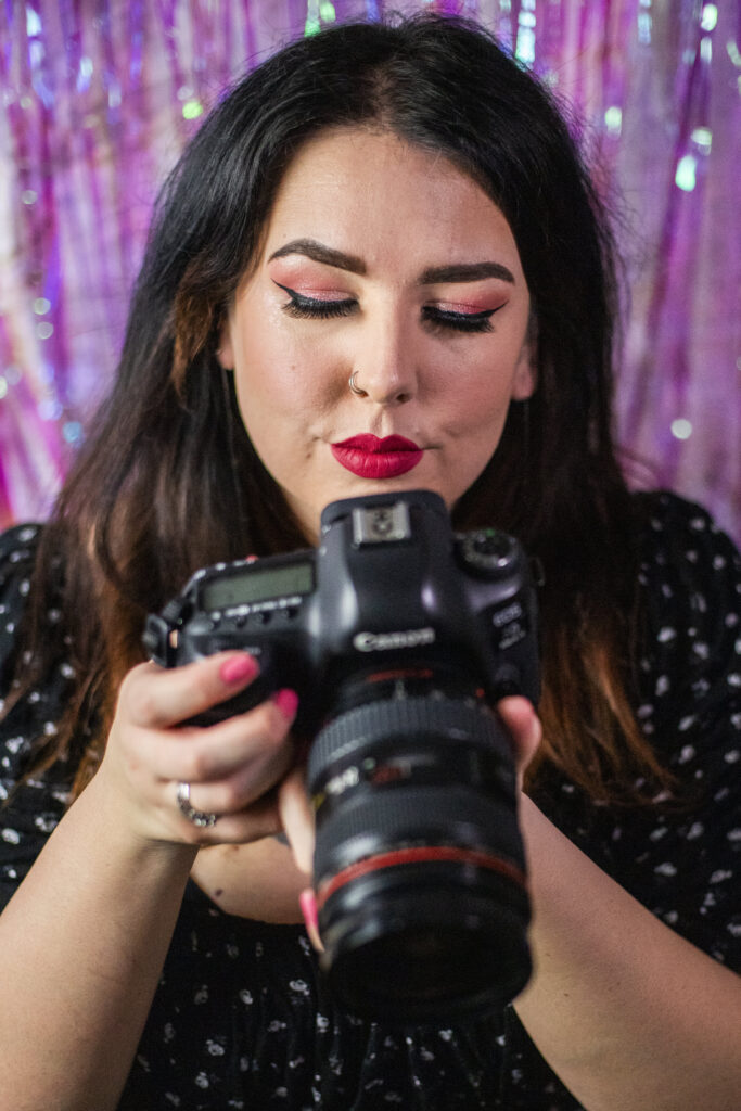 Photo of photographer holding camera against a purple sparkly background