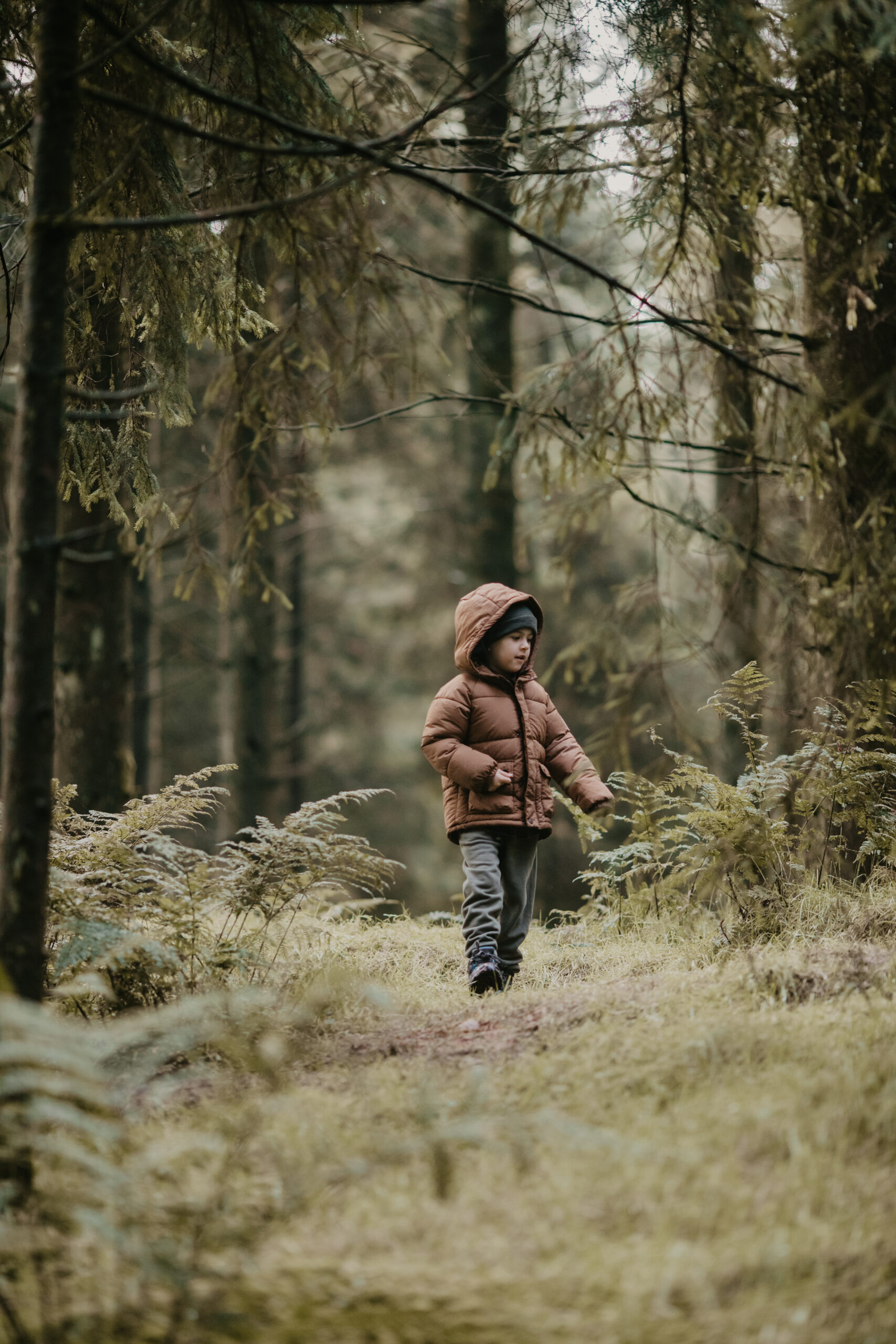 Photograph of a child in a brown coat in the forest, taken on a canon 135mm f2 lens