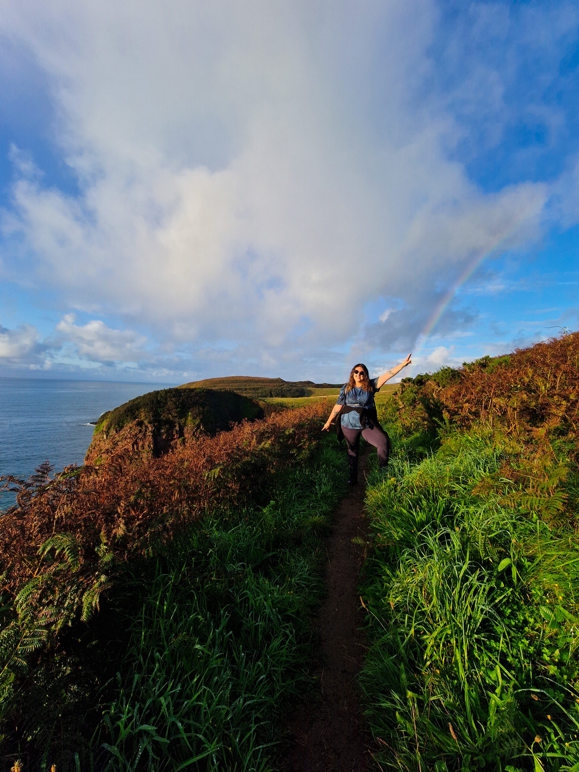 Hiker pointing at rainbow on Pembrokeshire coastal path