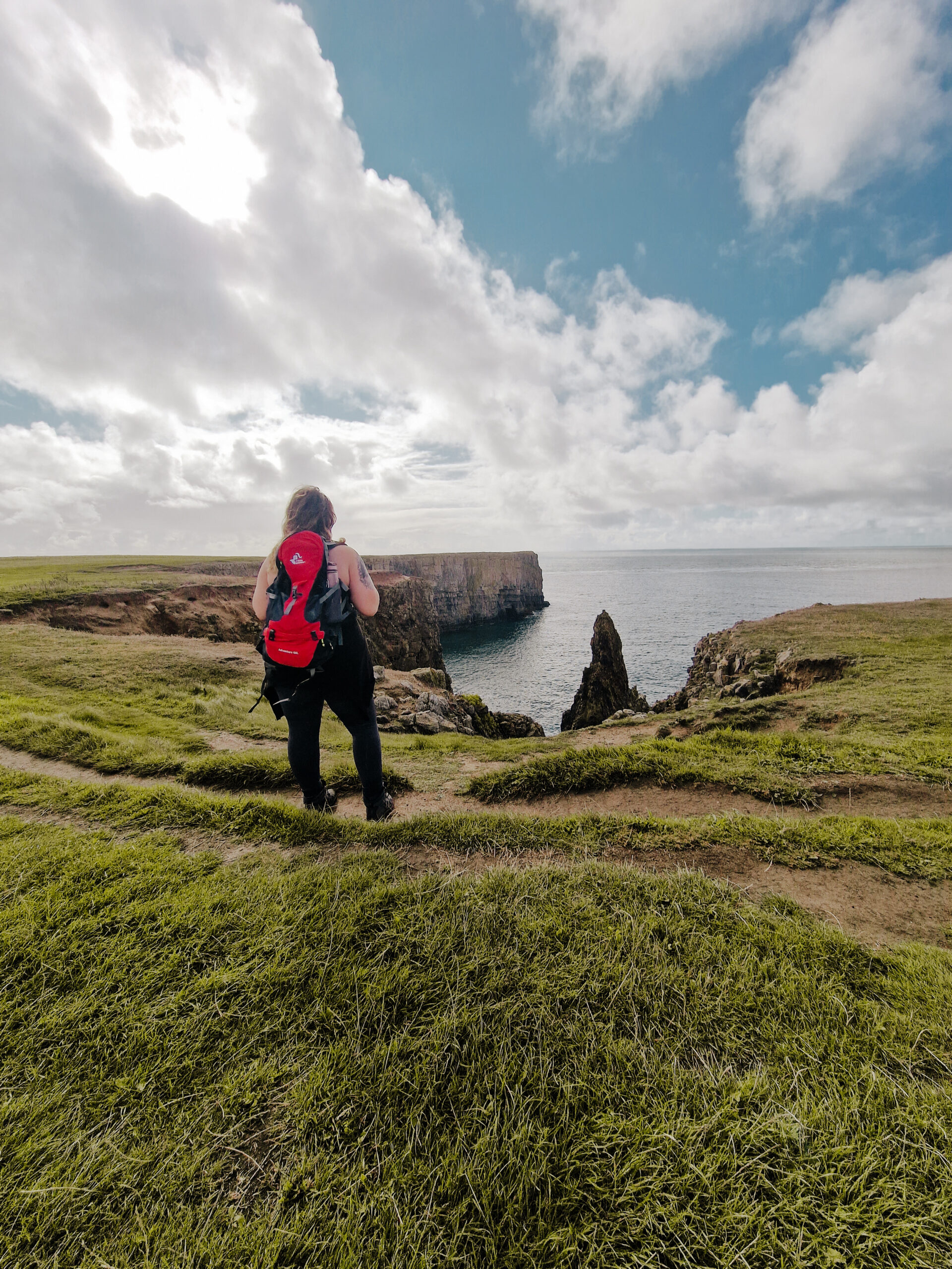 Hiker with a red bag on pembrokeshire coastal path