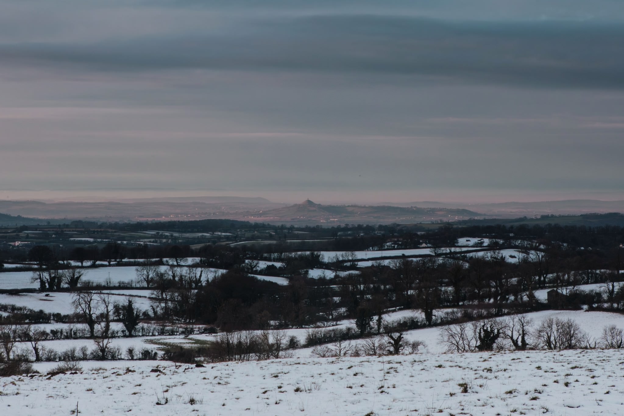 Picture of Glastonbury Tor during first light, taken from Beacon Hill woods in Shepton Mallet in the snow