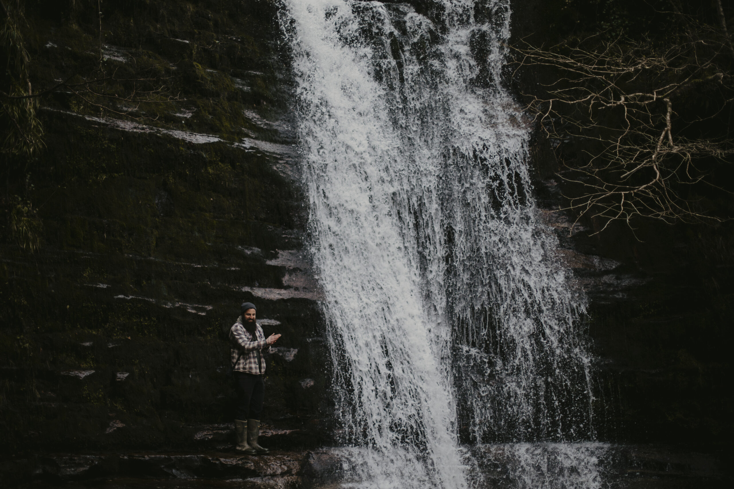 How to take good hiking photos - man standing next to waterfall